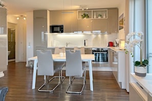 Una cocina moderna con comedor, armarios blancos y horno empotrado.