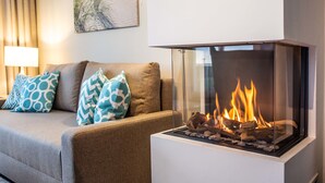A modern living room with a glass-fronted fireplace, a sofa with patterned cushions, and a wall-mounted lamp. - Apartment 'Villa Deichgraf 12 Meerblick' with Sea View, Balcony and Wi-Fi (Börgerende-Rethwisch)