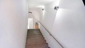 Un escalier avec une rampe, des murs blancs et une porte en haut.