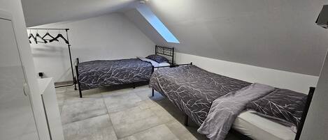 Un apartamento pequeño de una habitación con dos camas, un tragaluz y un armario.