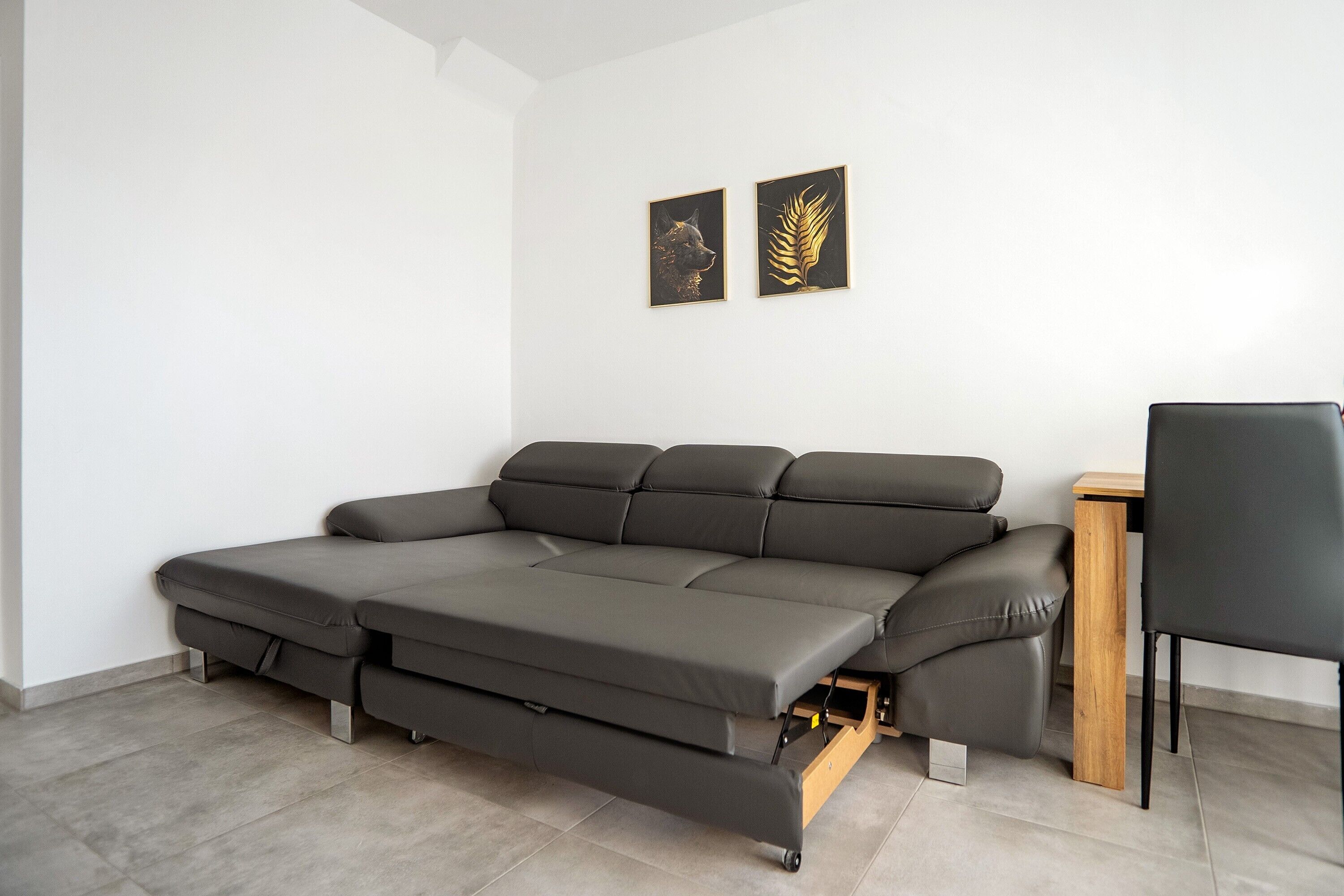 Ein modernes Zimmer mit einem grauen Sofa, einem Holztisch und zwei gerahmten Kunstwerken an der Wand.