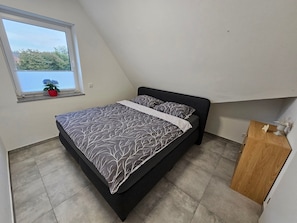 Un dormitorio con cama, una ventana con planta y un armario de madera.