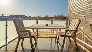 Un balcon avec une table et des chaises en verre, un mur en briques et une vue dégagée sur le ciel.
