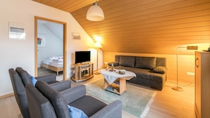 Una sala de estar acogedora con un sofá, sillones, una mesa de centro, un televisor y una lámpara.