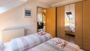 Un dormitorio con cama, radiador, armario y tragaluz.