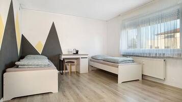 Una habitación con dos camas, un escritorio, una silla y un radiador.