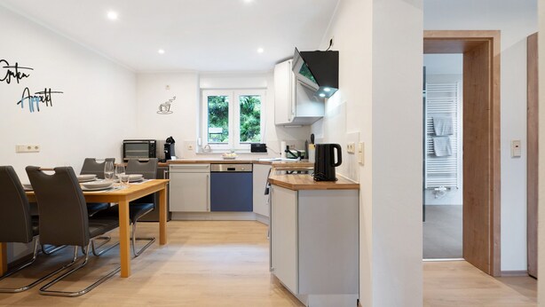 Une cuisine moderne avec un coin repas, une machine à café et une vue sur la verdure environnante.
