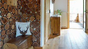 A wooden bench with a deer pillow, a wall of stacked logs, and a wooden cabinet with a plant. - Apartment 'Heimatglück 2, Maisonette, 76qm' with Shared Terrace, Balcony and Wi-Fi (Lautenbach)