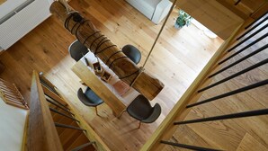 Un tavolo da pranzo in legno con sedie, un'amaca sospesa e una scala con ringhiere nere.