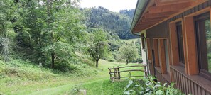 Una cabaña de madera con balcón que da a un valle exuberante y colinas boscosas.