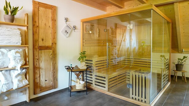 Una stanza sauna con travi in legno, un'area vetrata e una panchetta di legno.