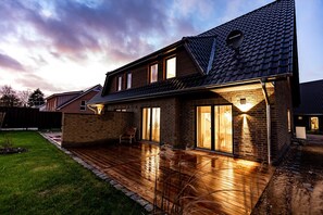 A two-story house with a wooden deck, brick walls, and a satellite dish.