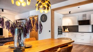 Un espace repas moderne avec une table en bois, des chaises et un vase contenant des fleurs violettes.