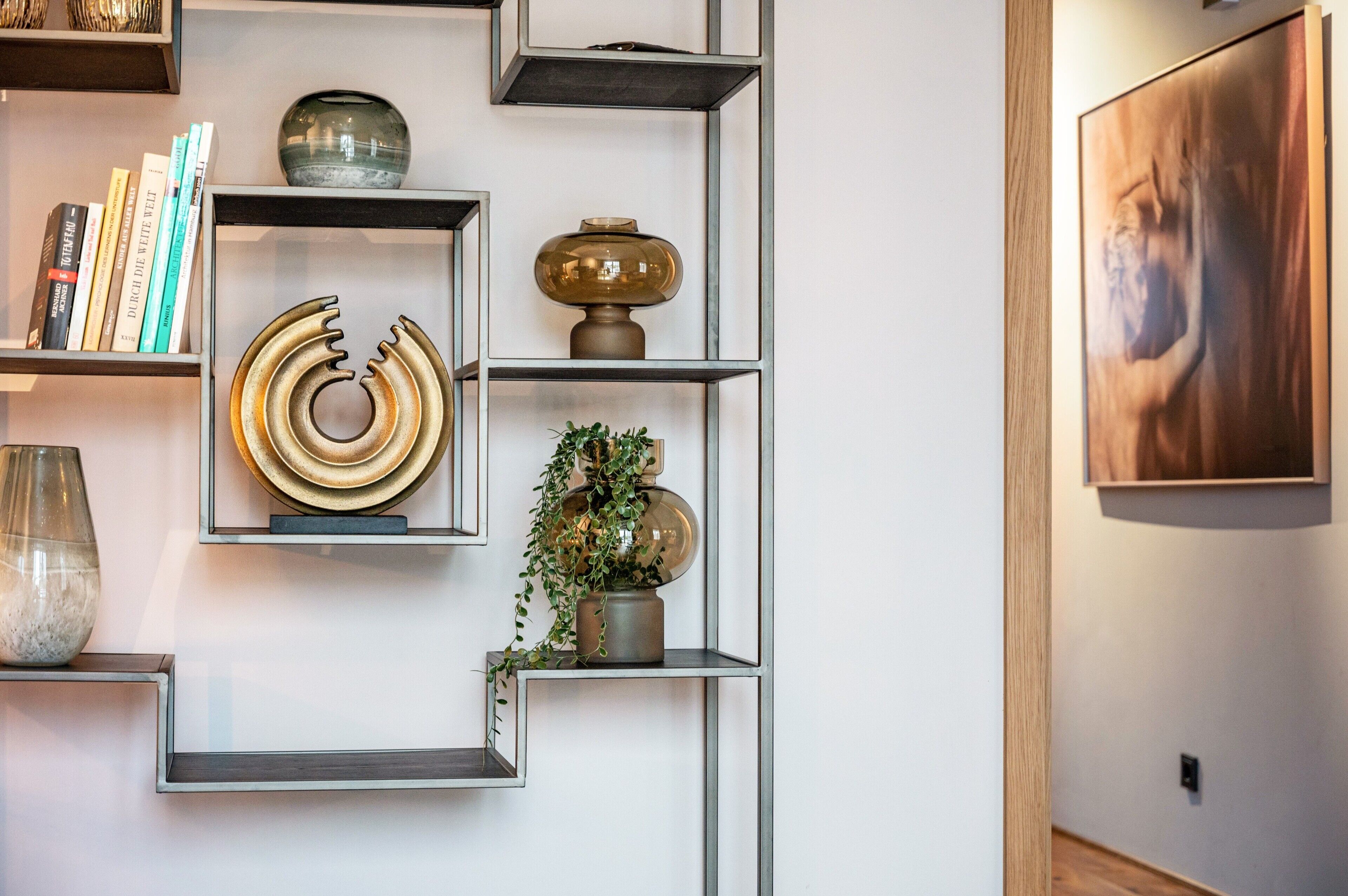 Ein modernes Interieur mit geometrischen Regalen, dekorativen Accessoires und einem gerahmten Kunstwerk an der Wand.