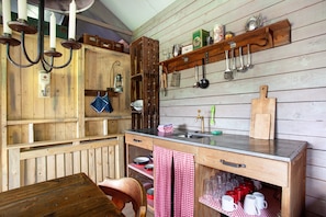 Une cuisine rustique avec des armoires en bois, une table en bois, un évier et divers ustensiles de cuisine.