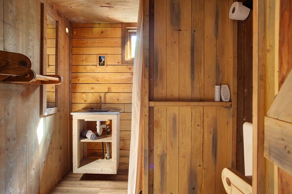 Interior de una cabaña de madera con un banco, un lavabo y un inodoro.