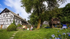 A traditional half-timbered house with a garden path leading to a wooden playhouse.