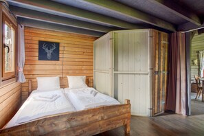 Une pièce en bois avec un lit, une armoire et une tête de cerf encadrée accrochée au mur.