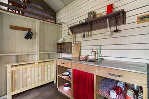 Une cuisine rustique avec des armoires en bois, un plan de travail en bois et un rideau rouge.