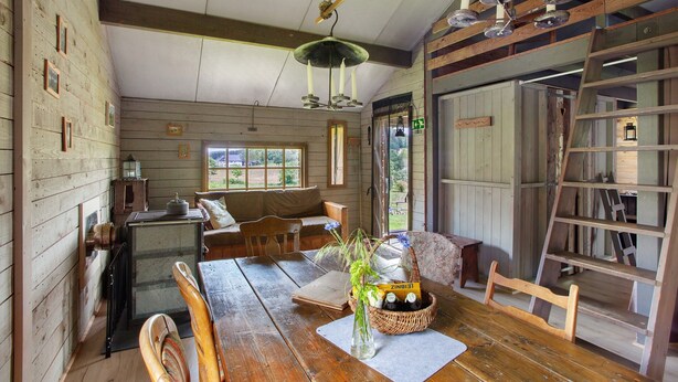 L’intérieur d’un chalet rustique, avec une table à manger en bois, une radio ancienne et un coin salon confortable.