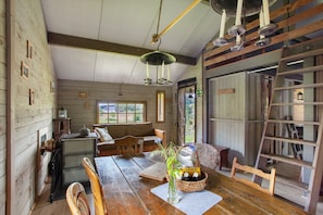 Interior rústico de una cabaña con una mesa de comedor de madera, una radio antigua y una zona de estar acogedora.
