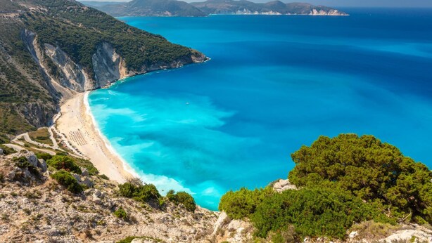 A coastal landscape with a clear blue sea, a sandy beach, and green hills. - Villa Thalia Katerina (Kefalonia)