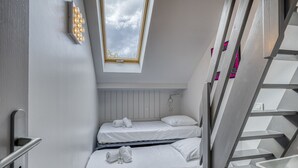 A compact room with two beds, a skylight, a staircase, and a wall-mounted light fixture. - La plage privée du lac (Duingt)