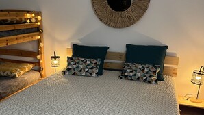 Une chambre avec un lit superposé, un miroir rond et deux tables de chevet avec des lampes.
