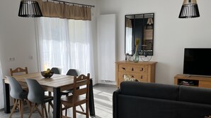 Un salon moderne comprenant un coin repas, un canapé, un téléviseur et une petite table agrémentée d’objets décoratifs.