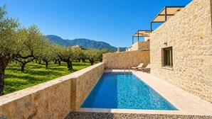 A swimming pool adjacent to a stone building with a view of mountains. - Villa Castillo Thio in Agios Nikolaos (West Mani)