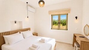 A bedroom with a wooden bed, a desk, a chair, a window with a view of trees, and a wall-mounted air conditioner. - Villa Castillo Thio in Agios Nikolaos (West Mani)