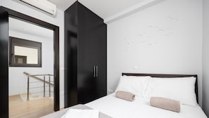 Habitación de hotel con cama, armario, espejo y escalera.
