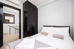 Ett hotellrum med en säng, en garderob, en spegel och en trappa.