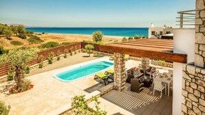 Une terrasse sur le toit avec une piscine, des espaces salons extérieurs et une vue sur la mer.