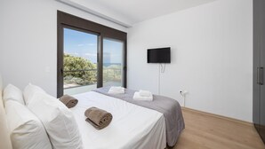 Une chambre à coucher avec un lit, des oreillers, une télévision et une fenêtre donnant sur un beau paysage.