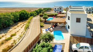 Une propriété située sur la côte, dotée d’une piscine, de chaises longues et offrant une vue sur la mer.