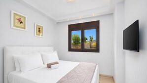A bedroom with a bed, a TV, and a window with a view.