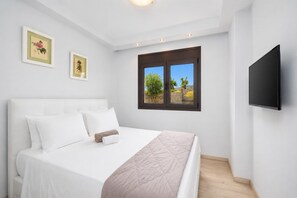A bedroom with a bed, a TV, and a window with a view. - Villa Dionysos in Rhodes (Rhodes)