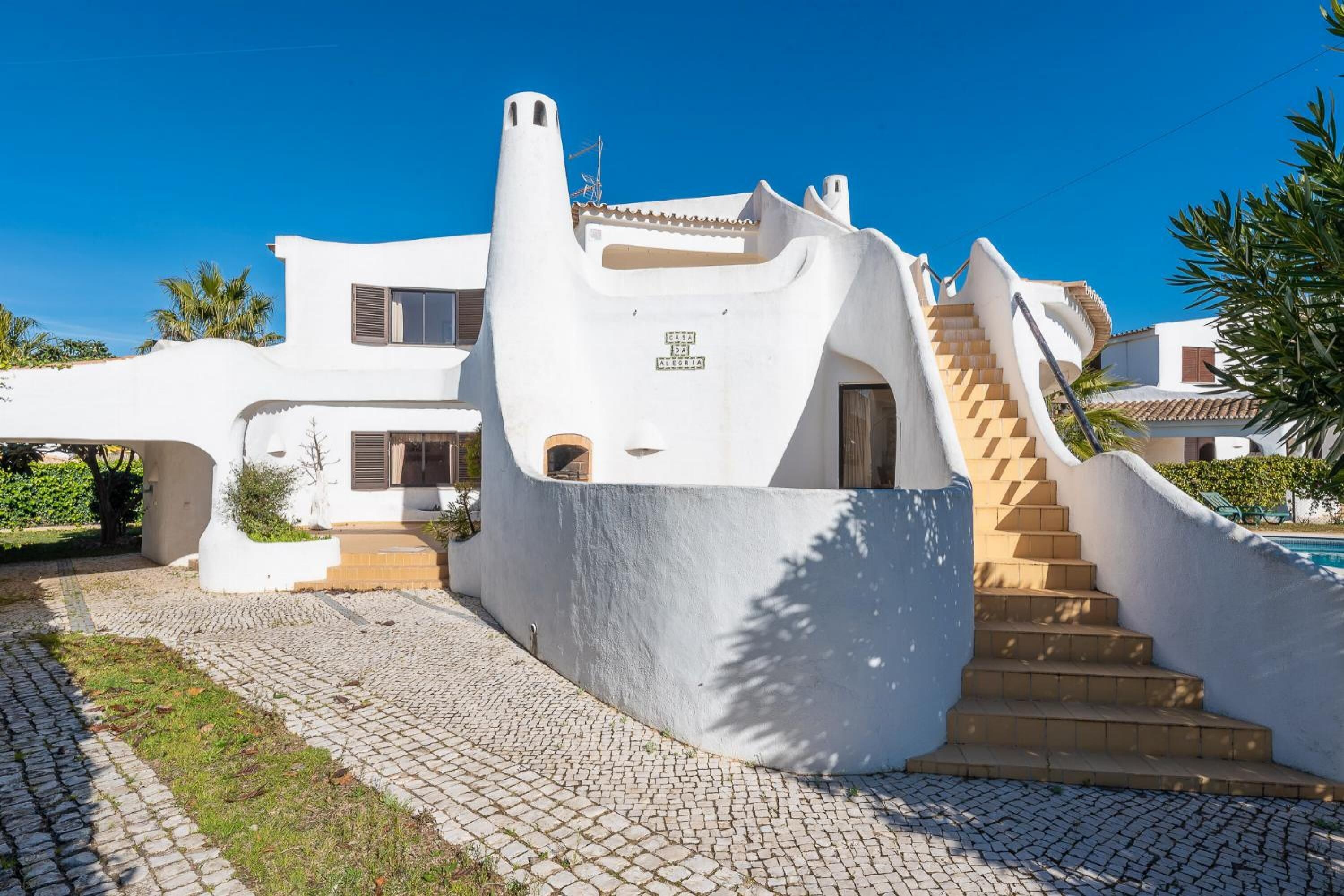 A modern white building with a unique architectural design, featuring a curved staircase leading to the entrance.