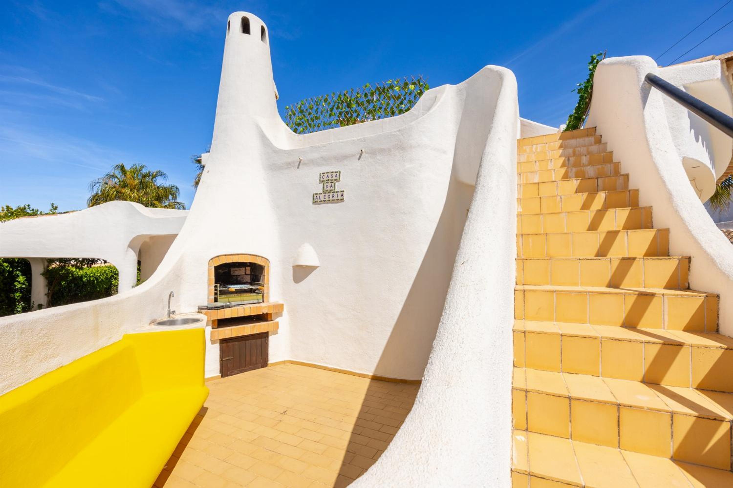 Um edifício branco com um design arquitetônico singular, incluindo uma parede curva e um conjunto de escadas.