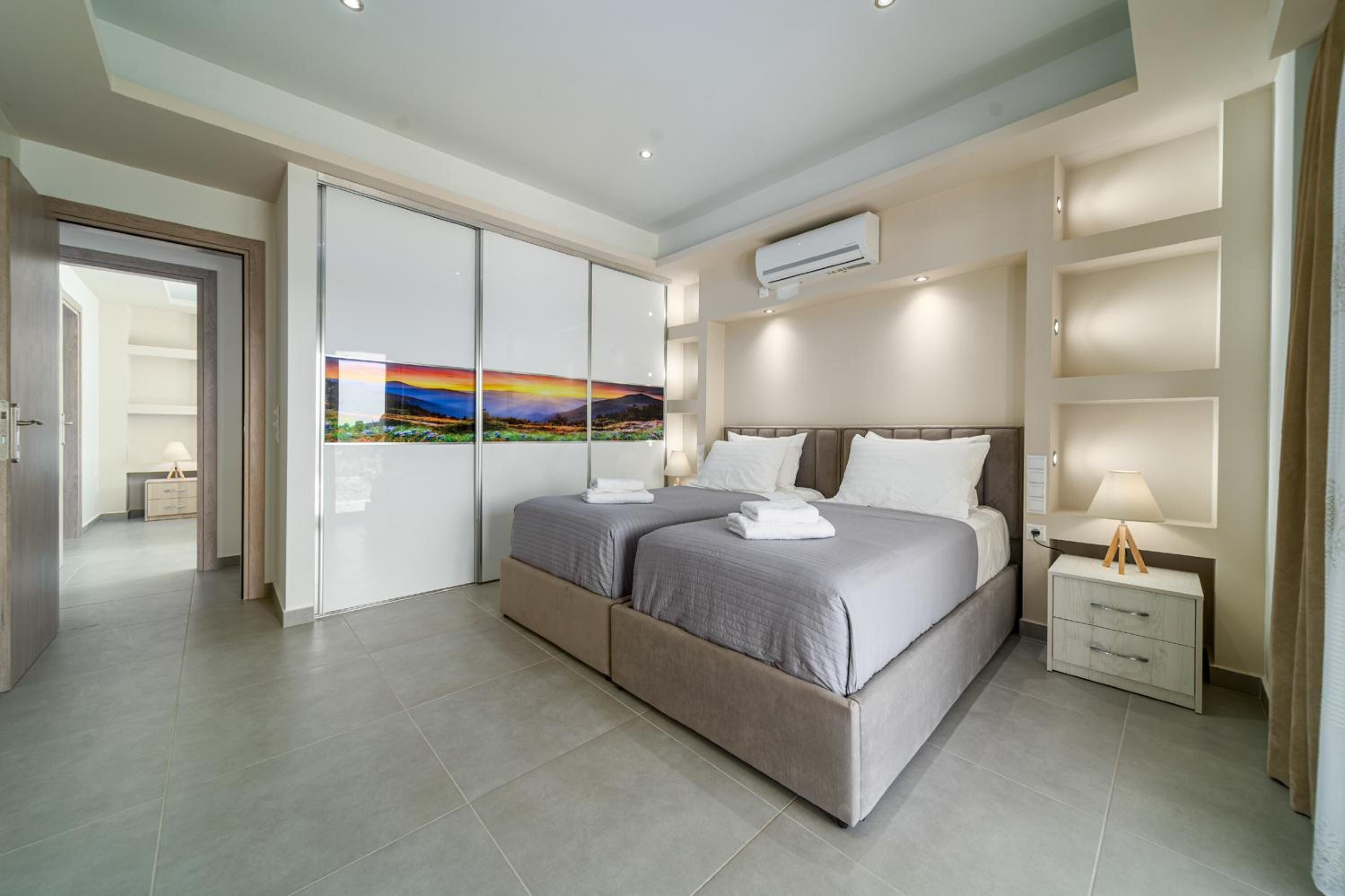 Ein modernes Schlafzimmer mit einem großen Bett, einem Nachttisch, einer Wand-Klimaanlage und einem Schiebetürenschrank.