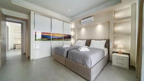 Un dormitorio moderno con una cama grande, una mesita de noche, un aire acondicionado instalado en la pared y un armario con puerta corredera.