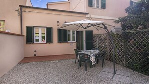 Un espace patio avec une table et des chaises sous une marquise, un petit jardin et un bâtiment portant le numéro « 352 ».