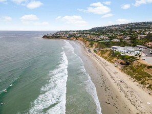 A coastal beach with a long stretch of sand, waves, and a hillside with buildings. - NEW Private PB Modern Cottage w/ Large Custom Deck (San Diego)