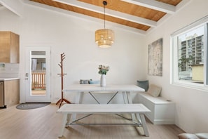 Un intérieur moderne avec une table à manger, un banc, un luminaire suspendu et une vue sur l’extérieur.
