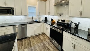 A modern kitchen with white cabinets, stainless steel appliances, and a black countertop. - Luxury Medical District Home, EV Charger, Gated #10 (Augusta)