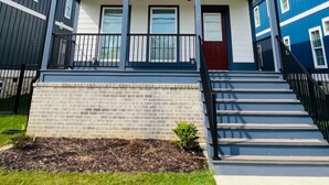 A two-story residential building with a balcony on the upper floor, a front door, and a staircase leading to the entrance. - Luxury Medical District Home, EV Charger, Gated #10 (Augusta)