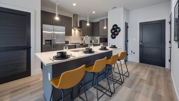 Een moderne keuken met een centraal eiland, barstoelen en hanglampen.