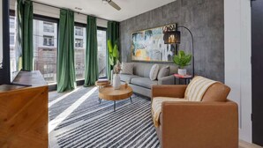 Een moderne woonkamer met een bank, fauteuil, salontafel en een schilderij aan de muur.