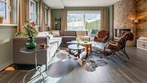 A modern living room with a stone fireplace, a sofa, a coffee table, and a view of the outdoors.